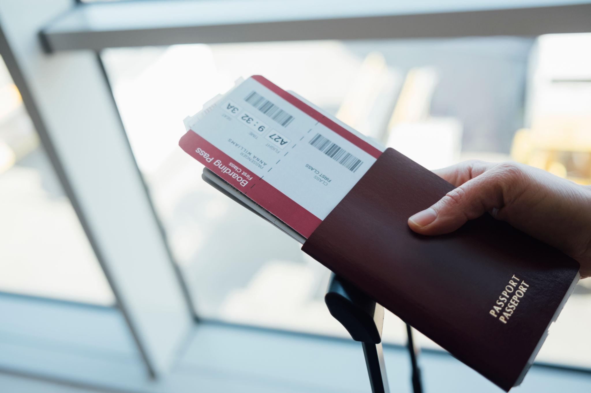 A hand holding a passport and boarding pass at the airport.